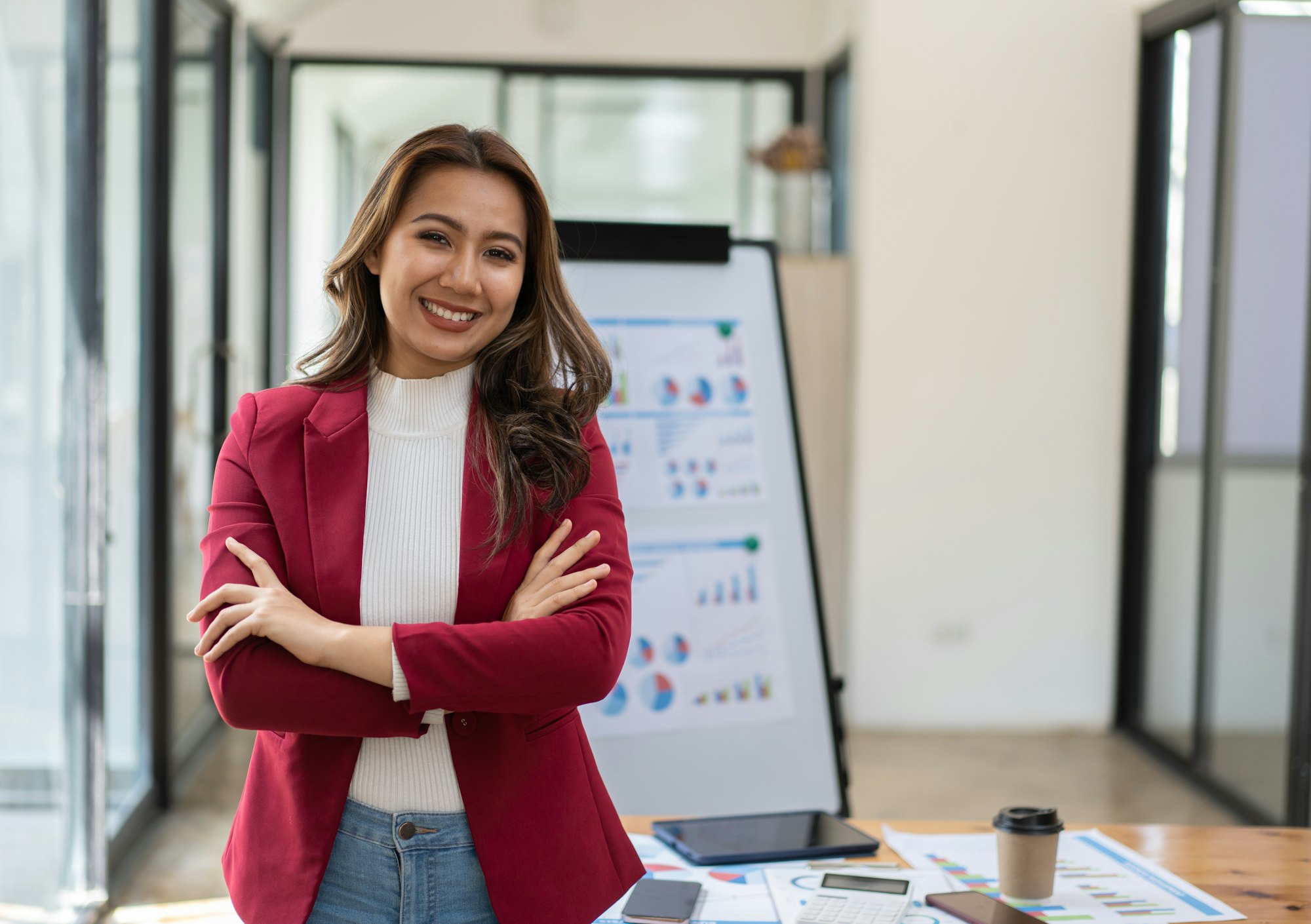 Confident Latin business leader portrait, Young businesswoman in suit posing with arms folded, looki