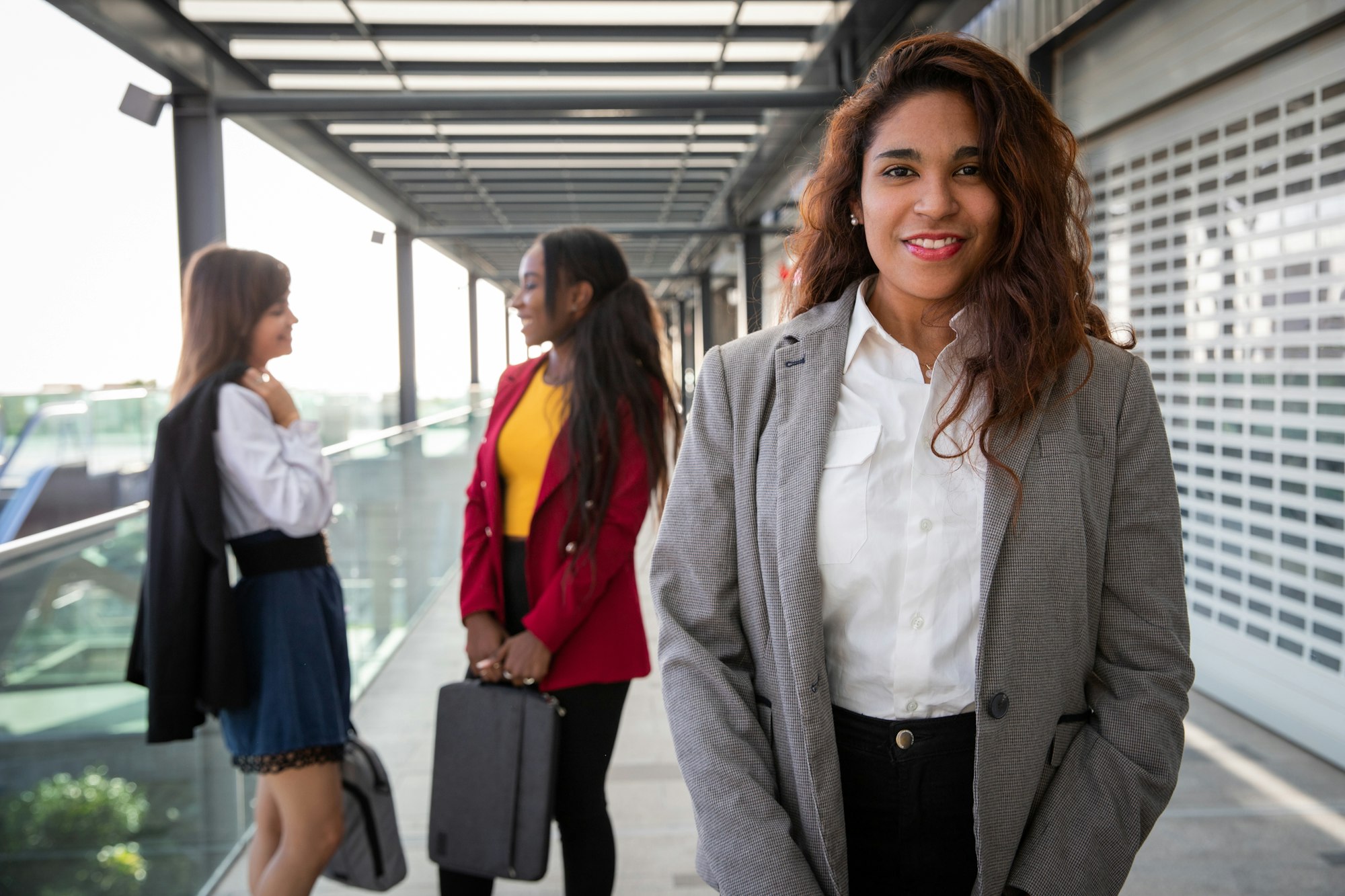 Portrait of a latina businesswoman with her colleagues behind her having a conversation.