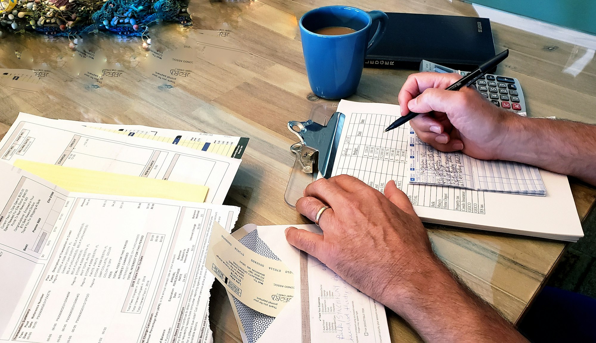 Retired man working on his federal taxes at desk with hot coffee and cellphone.